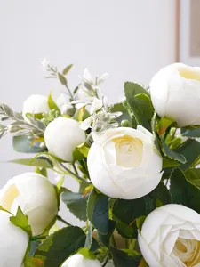 Detailed close-up of white artificial multi-headed peonies with lush green leaves.