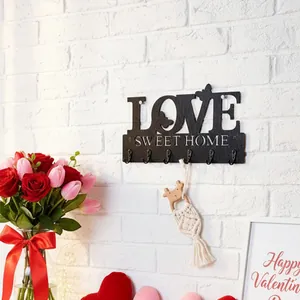 Detail der schwarzen LOVE SWEET HOME Holzhaken an einer weißen Ziegelwand montiert
