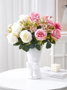 Detail of realistic pink and white silk roses arranged in a white decorative ribbon vase