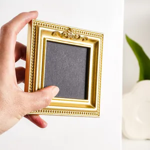 Close-up of hand holding a mini golden vintage European style resin photo frame.