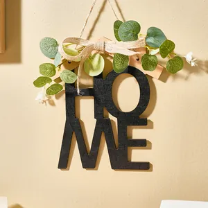 Detalle del colgante de pared HOME de madera con eucalipto artificial y lazo de arpillera