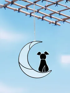 Decorative dog sitting on crescent moon ornament hanging outdoors against blue sky