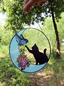 Detailed macro view of a stained glass suncatcher featuring a black cat and butterfly