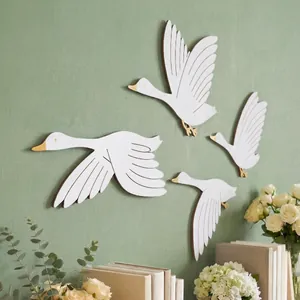 Detailansicht von vier eleganten fliegenden Gänsen aus Holz an einer salbeigrünen Wanddekoration
