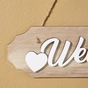Macro view of a rustic wooden welcome sign featuring a white heart and 3D lettering