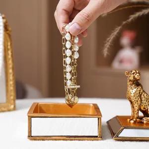 Détail boîte à bijoux miroir dorée avec ornement léopard et bracelet de perles