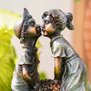Macro detail of vintage resin boy and girl kissing garden sculpture with bronze patina finish.