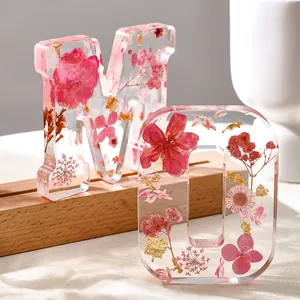 Primo piano di lettere in resina M e O con fiori rosa essiccati e scaglie d'oro