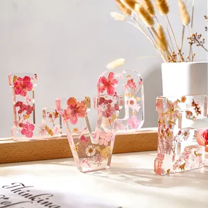 Dettaglio delle lettere LOVE in resina con fiori secchi e decorazione in foglie d'oro