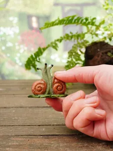 Detailed view of miniature resin snail garden ornament being held to show small scale