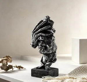 Primer plano de una escultura de rostro humano abstracto con acabado plateado metálico.