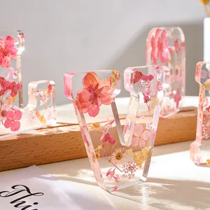 Dettaglio di fiori rosa essiccati incastonati in un ornamento in resina trasparente a forma V