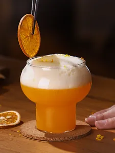 Detailansicht eines hitzebeständigen Glases in Kalebassenform mit schaumigem Cocktail