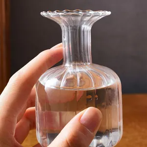 Detailed macro view of a fluted transparent glass vase with a flared rim held by a hand
