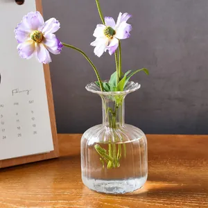 Detailed macro view of a clear ribbed glass vase featuring purple and white flowers