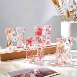 Dettaglio lettere HOME in resina trasparente con fiori secchi rosa e scaglie d'oro