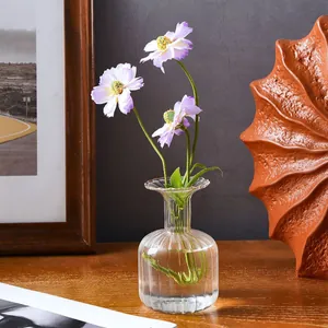 Detailed view of a clear ribbed glass vase with purple flowers on a wooden table