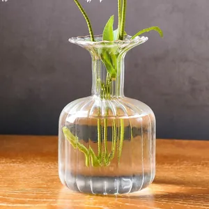 Close-up of clear ribbed glass vase in ink bottle shape with water