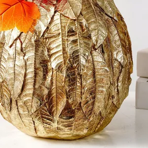 Gros plan sur un vase citrouille doré avec textures de feuilles pour décor de Moisson
