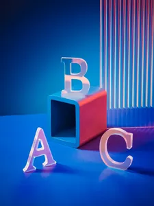Détail macro des lettres en acrylique irisé A, B et C sous un éclairage néon créatif