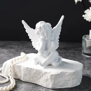 Detailed macro shot of a white resin angel figurine sitting on a decorative stone block