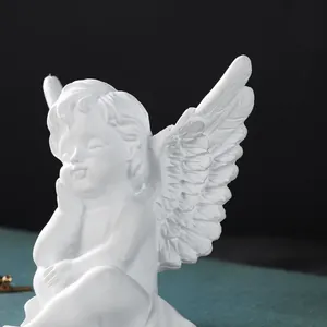 Close-up detail of a white resin angel figurine showing delicate wing textures