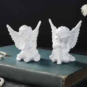 Macro view of white resin cherub angel figurines on a vintage book for home decor