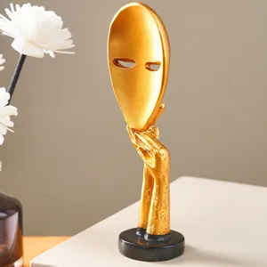 Detailed close-up of a golden abstract Silence is Gold face mask resin figurine for home decor
