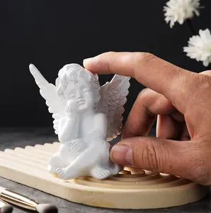 Detailed view of a small white resin angel figurine held by hand for size reference