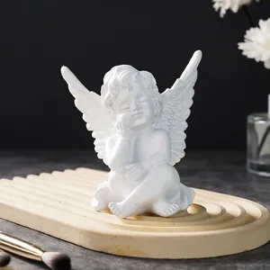Close-up of a delicate white resin angel figurine sitting on a stylish wavy tray decor