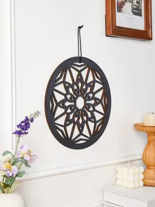 Detail view of the round black wooden geometric wall hanging art displayed in a cozy interior scene.