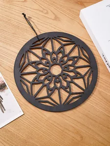 Close-up of black hollow carved wooden bohemian hanging decor with geometric floral pattern.