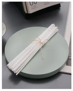 Primer plano de varillas difusoras de fibra blanca atadas con un cordel minimalista.