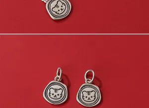 Detailed close-up of matte S925 silver tiger head charms on a vibrant red background