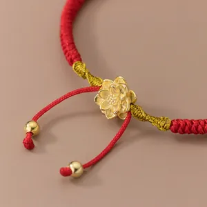 Bracelet tressé rouge fait main avec breloque fleur de lotus dorée et perles dorées.