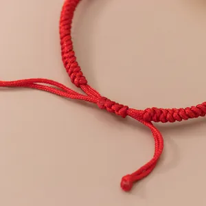 Bracelet en fil rouge tressé à la main avec le détail précis du nœud coulissant réglable