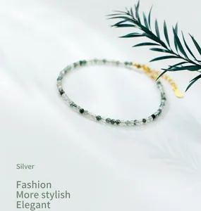 Macro detail of natural green moss agate beads on a delicate gold-plated silver chain.