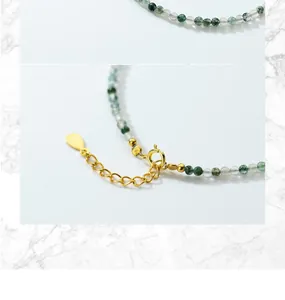 Macro view of gold-plated clasp and natural moss agate beads on adjustable bracelet