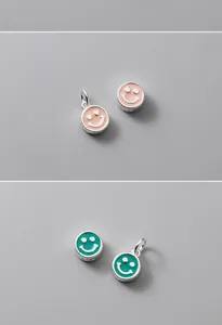 Macro view of S925 sterling silver smiley face charms with colorful pink and teal enamel.