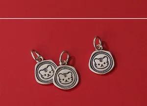 Close-up of vintage-style S925 silver charms featuring cartoon tiger heads on red background
