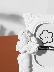 Detailed view of a white resin photo frame featuring a carved cherub angel sculpture