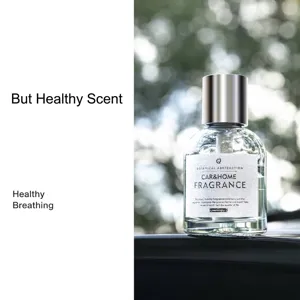 Flacon de parfum de voiture en verre haut de gamme avec bouchon argenté sur fond nature.