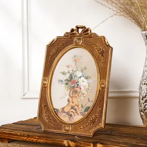 Prunkvoller Vintage-Goldharz-Fotorahmen mit Blumen-Putten-Kunst auf rustikalem Holz