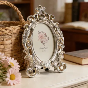 Ornate vintage silver oval photo frame with intricate baroque carvings on a classic wooden desk