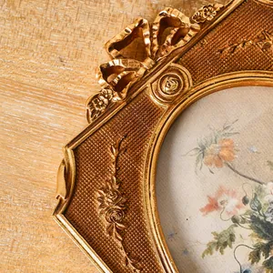 Detailaufnahme eines goldenen Fotorahmens aus Harz mit filigranen Blumen- und Schleifenverzierungen