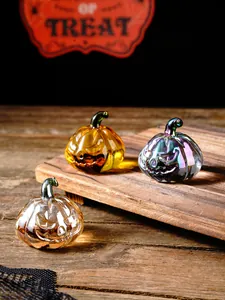Detailed macro shot of iridescent and amber glass pumpkins for festive Halloween tabletop decor.