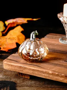Detail view of an amber glass Halloween pumpkin ornament with a carved face on a wood stand