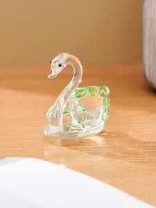 Detailed view of a clear crystal swan figurine with elegant green accents on a wooden desk.
