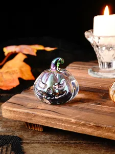 Close-up of an iridescent glass jack-o'-lantern pumpkin on a wooden board with a candle
