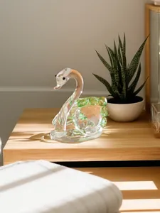 Detailed view of an elegant green and clear crystal swan figurine on a wooden bedside table